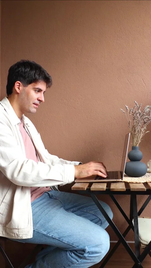 Vertical Young smiling Hispanic man typing on laptop keyboard working from ho Stock Footage 319027713