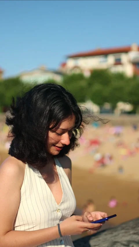 Vertical Young woman using smartphone near beach Stock Footage 313554724