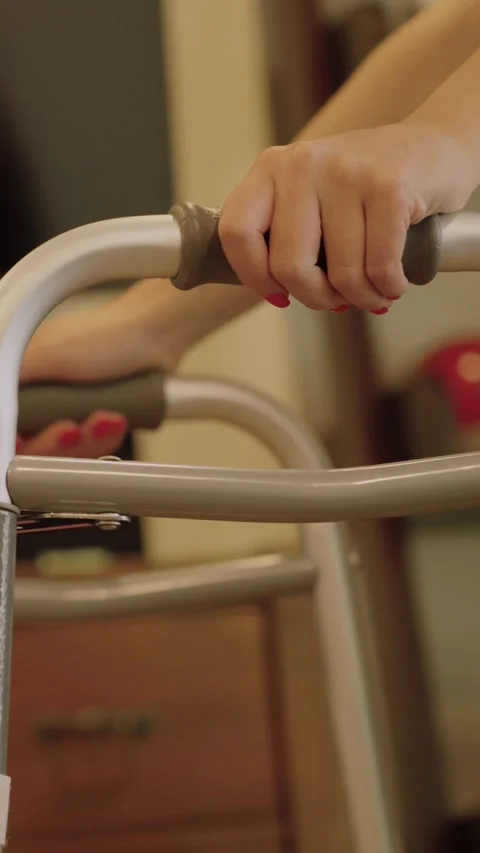 Vertical Young womans hands pushing walker through living room Stockbeeldmateriaal 284033560