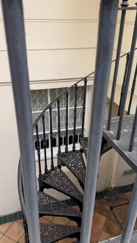 Vertical zoom shot through a metal gate looking down at outdoor spiral stairs Stock Footage 336539033