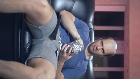 Vertically. balding man at home in a chair with a beer and a remote control. Stock Footage 134332032
