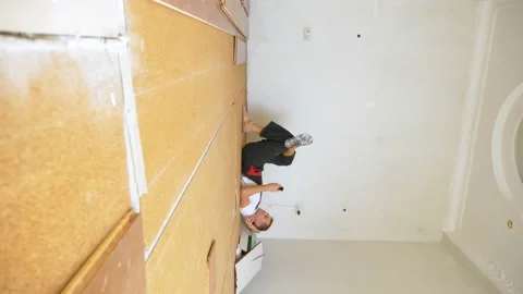 Vertically. Builder in renovated room lying on floor using smartphone Stock Footage 146658079
