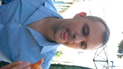 Vertically. handsome man eating pizza in a cafe outdoors Stock Footage 140520111