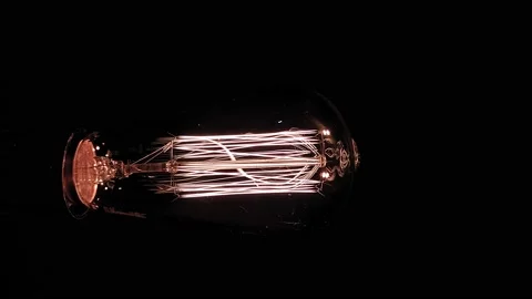 Vertically. An incandescent lamp with a tungsten coil on a black background lies 库存影片 141817192