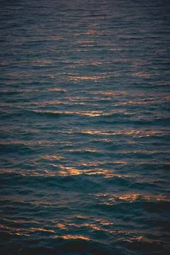 A vertically oriented abstract photograph of sunrise hitting the waves at sea Stock Photos