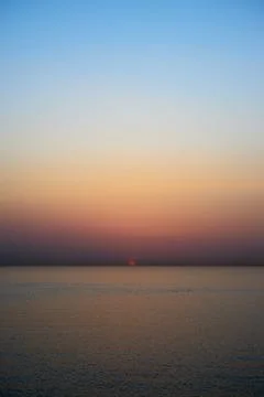 A vertically oriented photo of a beautiful calm sea and sky at sunrise Stock Photos