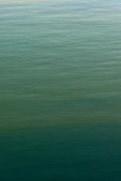A vertically oriented photo of a calm green sea as a background Stock Photos