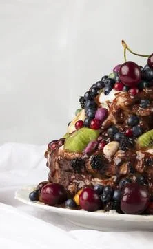 Vertically part of a cake decorated with various fruits and berries. Stock Photos