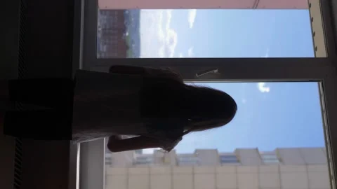 Vertically. silhouette. girl is stretched by the window with a view of the sky Stock-Footage 130489015