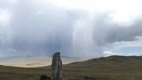Vertically standing stone on a hilly plain against a rainy cloudy sky. Stock Footage 82221538