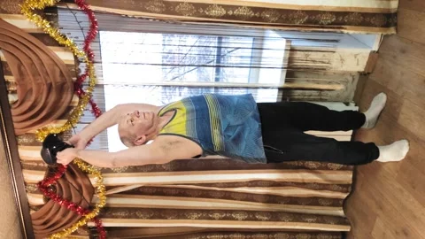 Vertically video. A man in training at home with shakes muscles with an iron Stock Footage 142393346