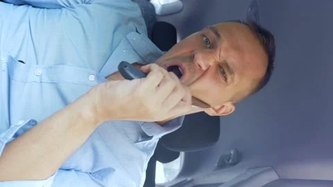 Vertically. Young handsome man shaving with knife while sitting in car in Stock Footage 142094335