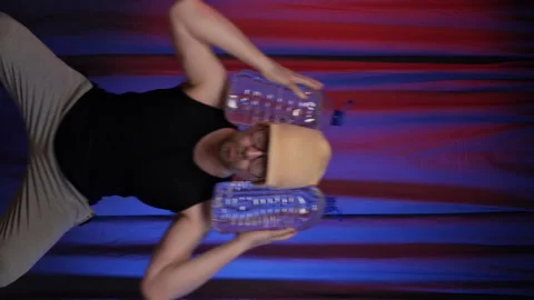 Vertical.Man performs back squats using large bottles of water as a weight. Stock Footage 136871363