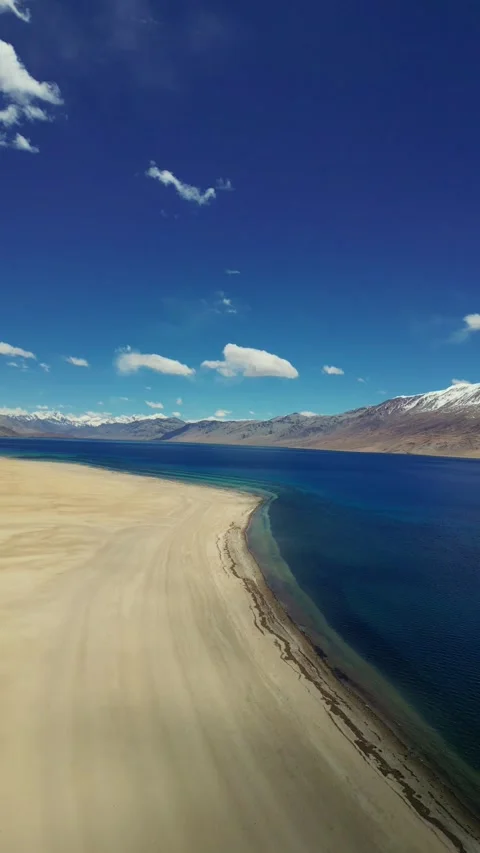 Verticle drone view of Tso Moriri’s deep blue waters surrounded by snow-kissed Stock Footage 310807140
