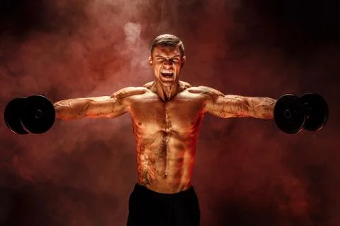 Very brawny guy bodybuilder, execute exercise with dumbbells, on deltoid muscle Stock Photos