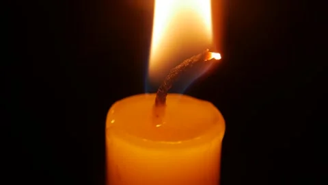 A very close macro view highlights the textured wick of the candle while gentle Stock Footage 324802645