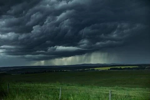 Very dark and dramatic storm clouds over a rape seed field. Stock Photos