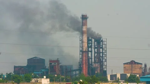 Very dense black smoke is coming out of the chimney of a big industrial site. Ai Stock Footage 321859802