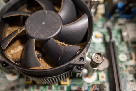 A very dirty computer fan inside a computer is cleaned by a vacuum cleaner Stock Photos