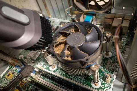 A very dirty computer fan inside a computer is cleaned by a vacuum cleaner Stock-Fotos