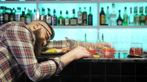 A very drunk young man is lying with his head on a table in a bar. A drunk man Stock Footage 168623800