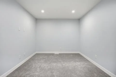 Very empty room with a white wall and grey carpet Stock Photos