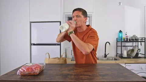 A very hungry starving man quickly eats groceries food in a modern kitchen using Video stock 278027233