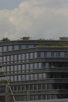 A very large building that features numerous windows and has trees on its roof Fotos de archivo