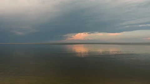 A very large calm lake reflects the late afternoon sky with grey-blue clouds  Stock Footage 156516596