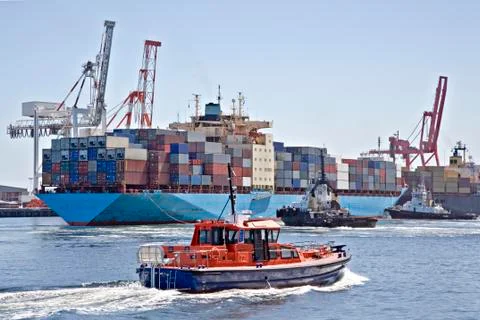 Very large container ship being berthed by two tugs Stock Photos
