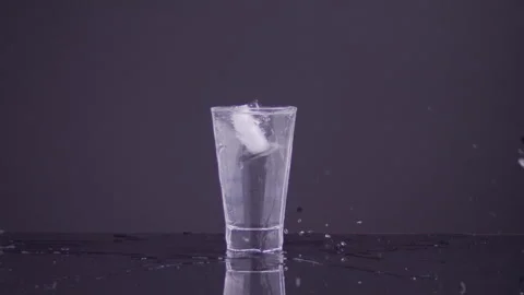 Very Large ice cube falling in a glass of water and splashing in slow motion. Stock Footage 273124389