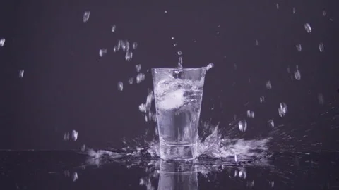 Very Large ice cube falling in a glass of water and splashing in slow motion. Stock Footage 273146321