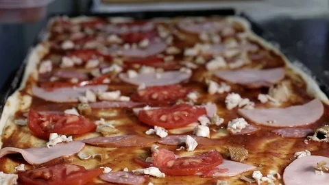 On a very large rectangular pizza with meat, bacon, tomatoes and mushrooms Stock Footage 102709145