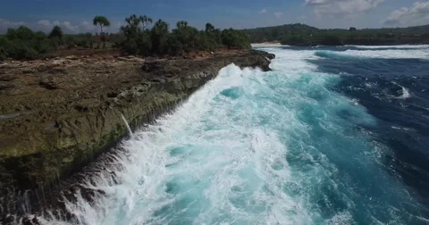 VERY LOW ANGLE 4K AERIAL FOLLOWING OCEAN WAVES ALONG LIMESTONE CLIFF Stock Footage 60041744