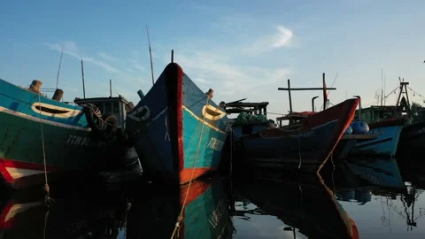 Very low angle aerial pan across fishing boats anchoring at sunset Stock Footage 147983948