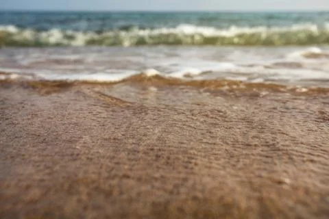 Very low angle (camera on ground, close up) sea water washing the sand. Selec Stock Photos