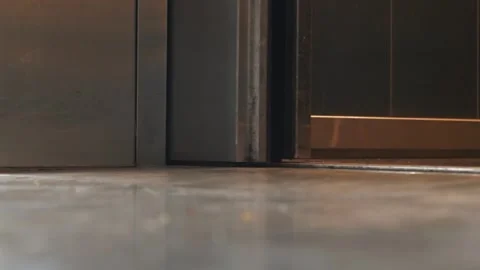 A very low-angle, close-up view of a metal elevator door opening onto a shiny Stock Footage 322891245