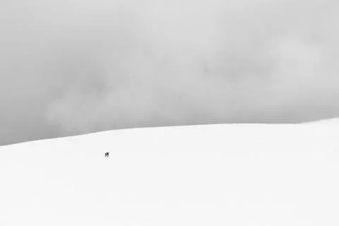A very minimalistic view of two distant people over a mountain covered by snow Stock Photos