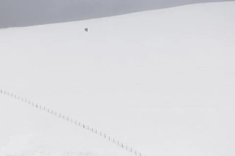 A very minimalistic view of two distant people over a mountain covered by snow Stock Photos