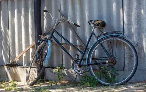 A very old and rusty Soviet bicycle, standing by a steel fence. Nobody will Stock Photos