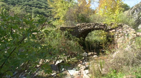 Very old crumbling stone bridge over mountain stream Stock Footage 56128014