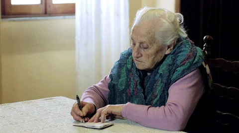 Very old lady writing something on little notepad: aged, house, inside, ancient Stock Footage 37908118