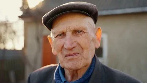 A very old man is sad and depressed in the sun on the background of the house Stock Footage 227540979