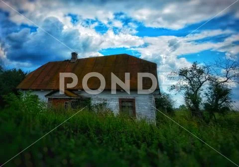 Very old uninhabited decrepit house overgrown with wild vegetation Stock Photos