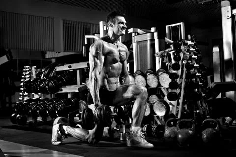 Very power athletic guy , execute exercise with  dumbbells, in gym Stock Photos