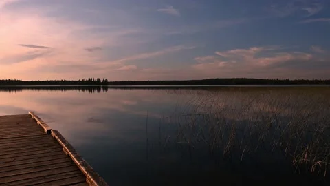 Very quiet lake at sunset with small ripples in the water and a wooden dock Stock Footage 220814712