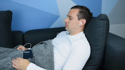 Very Relaxed Man Lying on the Couch Listening to Meditation Music Video stock 113223077