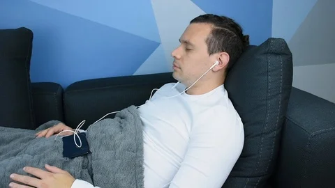 Very Relaxed Man Lying on the Couch Listening to Music to Meditate Stock Footage 113223099