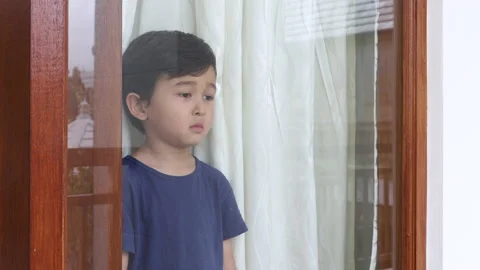 Very sad boy standing behind window. Quarantine. Self-isolation. Punishment Stock Footage 162009145