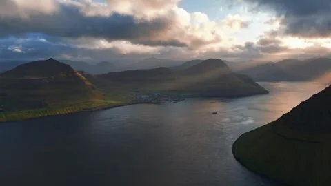 Very slow orbit approach above Faroese fjord landscape during golden evening Видео 335179764